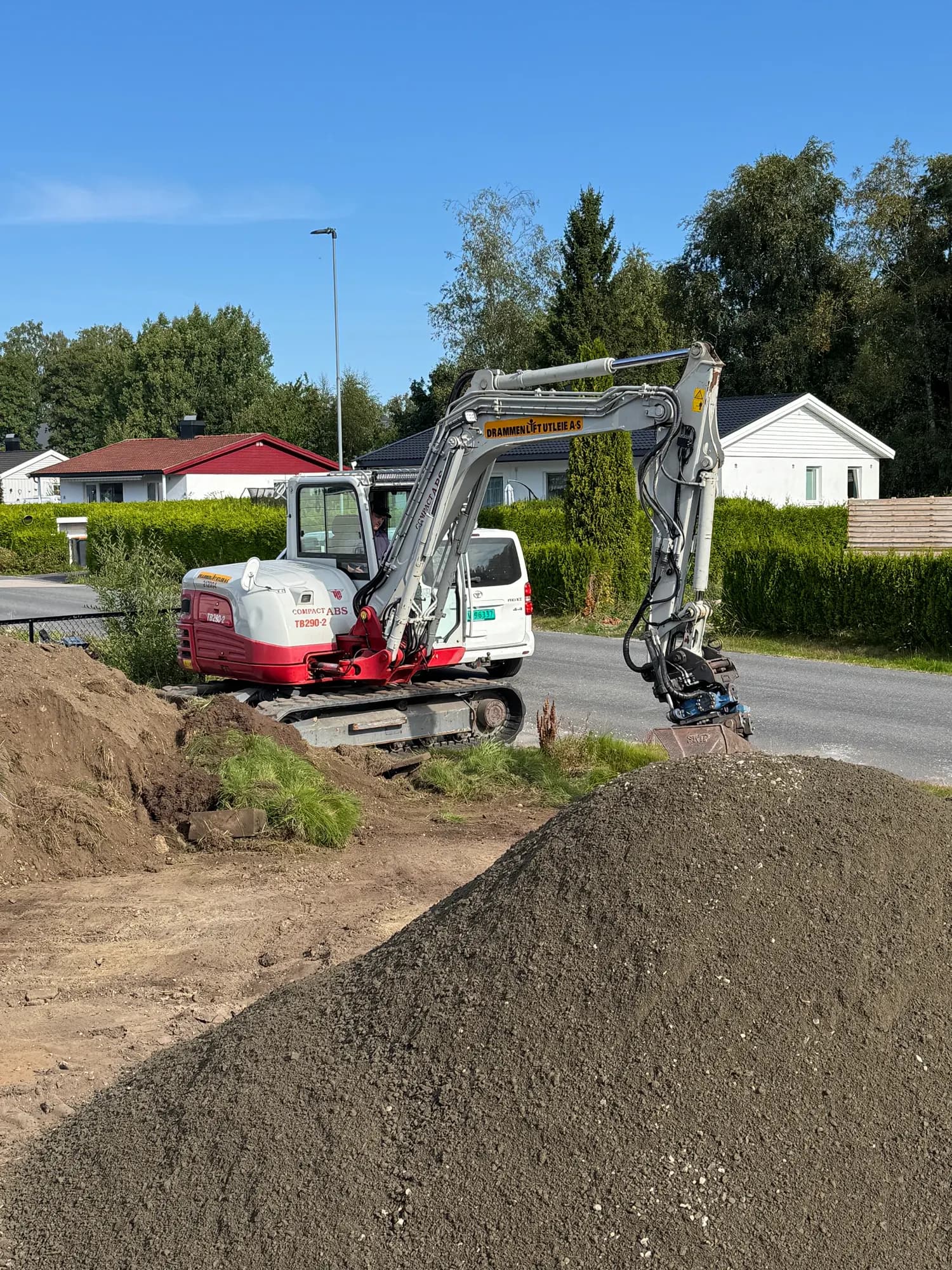 Gravemaskin i arbeid på massehaug ved boligfelt