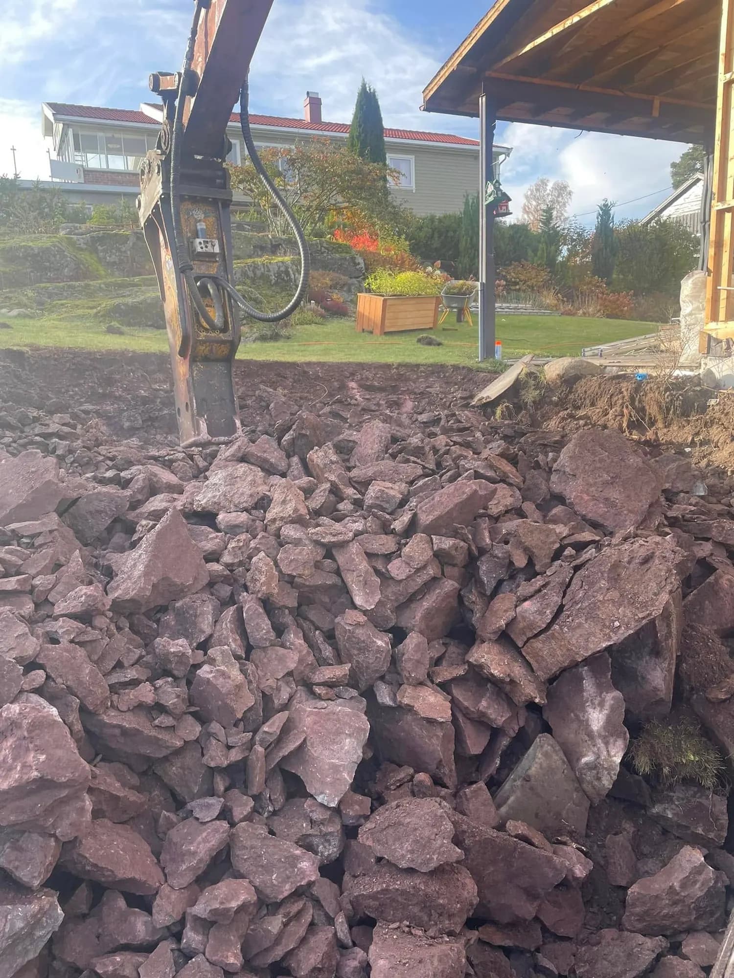Oppgravde steinmasser løftes med gravemaskin